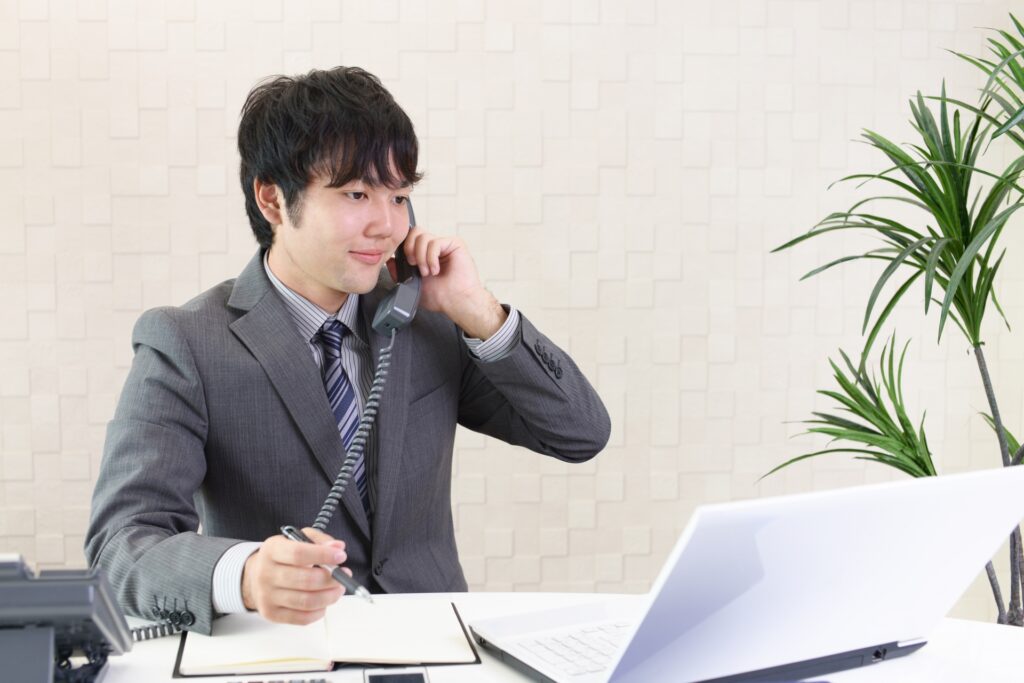 メモを取りながらビジネスマナーに即した電話対応をする新入社員の男性